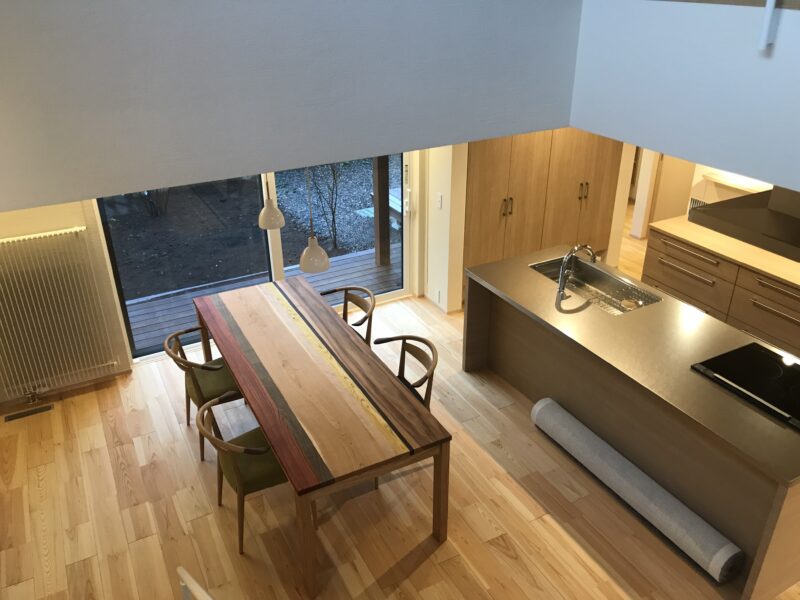 階段から見下ろす、ダイニングテーブル（無垢いろいろ樹種）、アイランドキッチン（SUSバイブレーション）、輻射暖房（パネルヒーター）